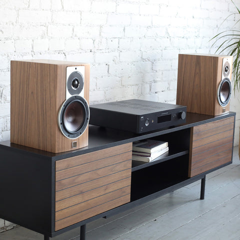 NAD C389 Amplifier on credenza beside DALI Rubicon 2 Bookshelf Speakers