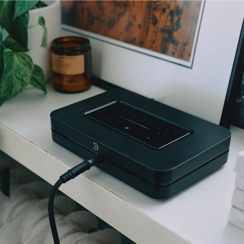 Bluesound Node (N132) Black - on a shelf with a pair of headphones plugged in