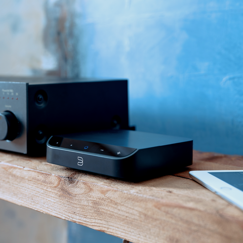 Bluesound Node Nano on table connected to vintage amplifier