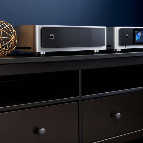 NAD M23 power amplifier beside NAD M33 amplifier on a credenza