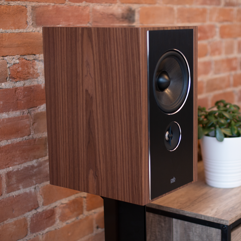 PSB Synchrony B600 Satin Walnut on stand beside credenza