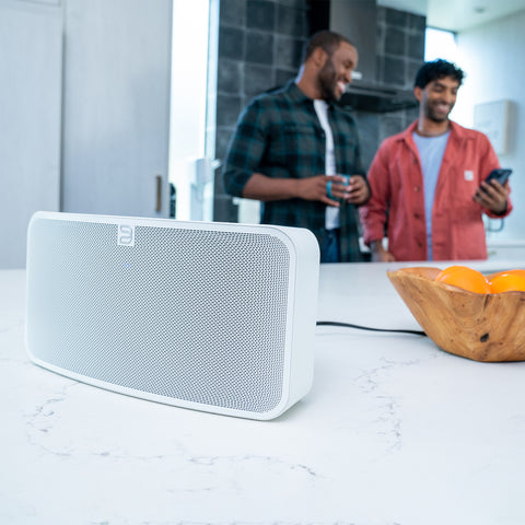 Bluesound Pulse 2i White on kitchen counter with two men standing behind it