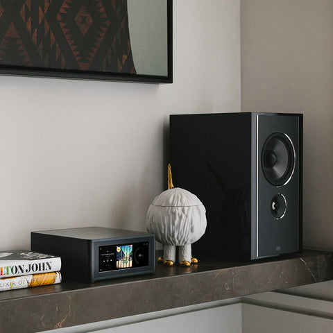 NAD M10 V3 on a shelf beside PSB Imagine B50 Bookshelf Speaker