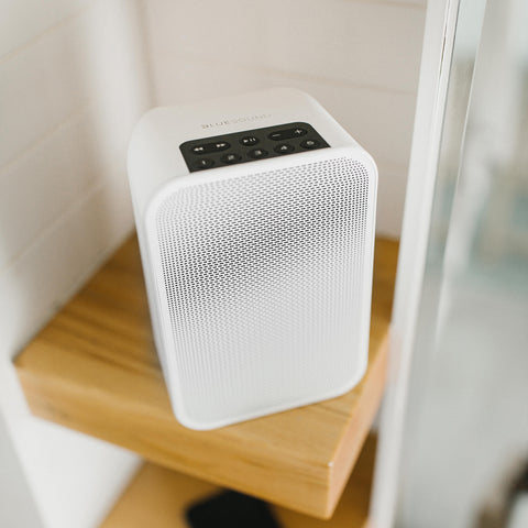 Bluesound Pulse Flex 2i White on a wood shelf