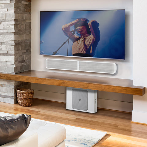 Bluesound Pulse Soundbar Plus White wall mounted below a TV with a Pulse Sub Plus White below a shelf