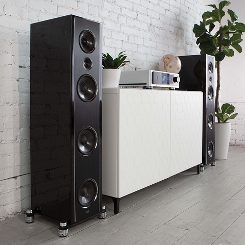 PSB Synchrony T600 high gloss black tower speakers on either end of a white credenza with an NAD M33
