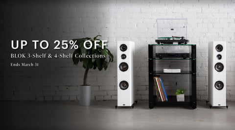 Home audio system with speakers and Black BLOK shelves against a white brick wall, promotional text overlay. Up to 25% off 3-shelf and 4-shelf collections. Ends march 31.